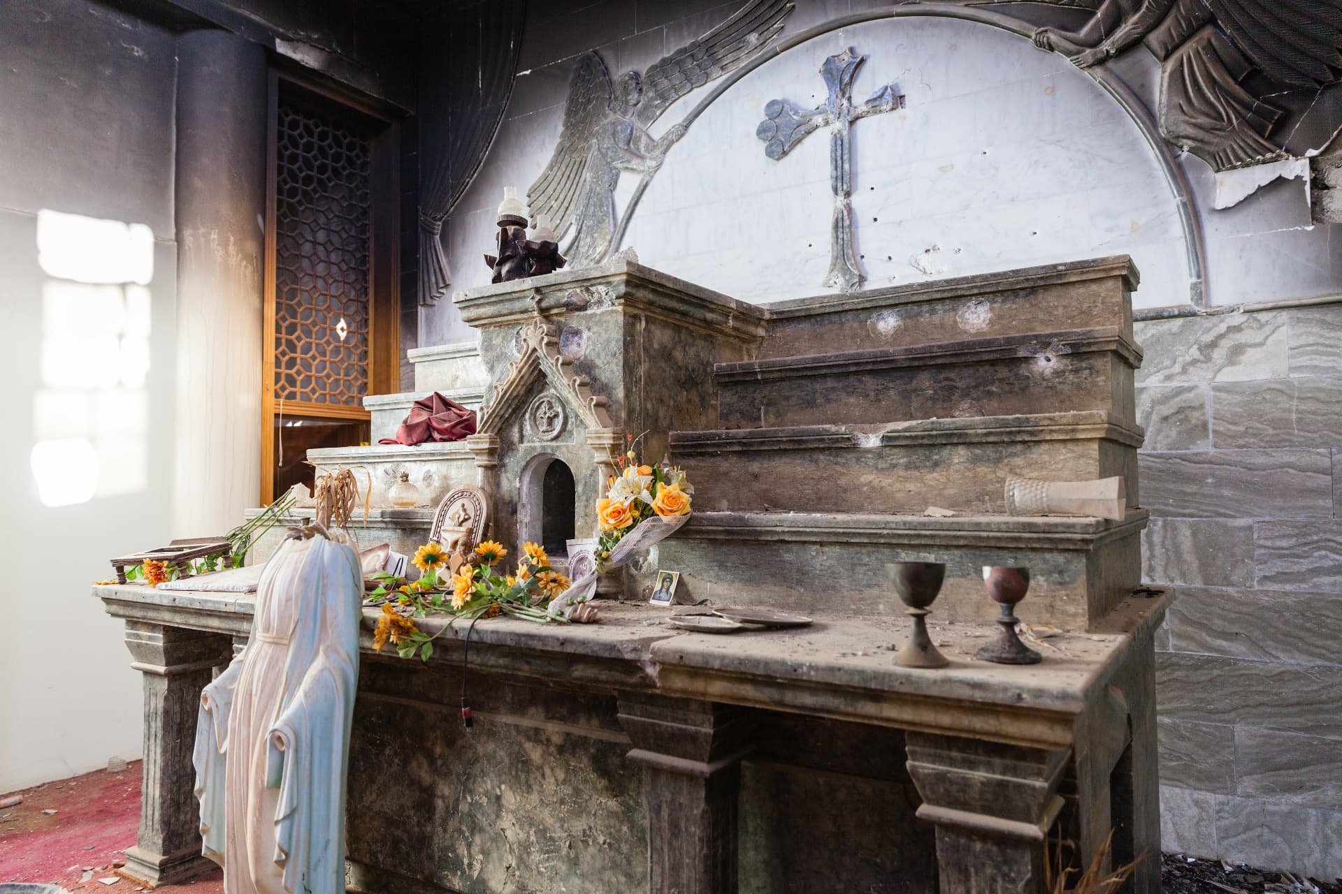 Verwoest altaar met beschadigd Mariabeeld in een kerk